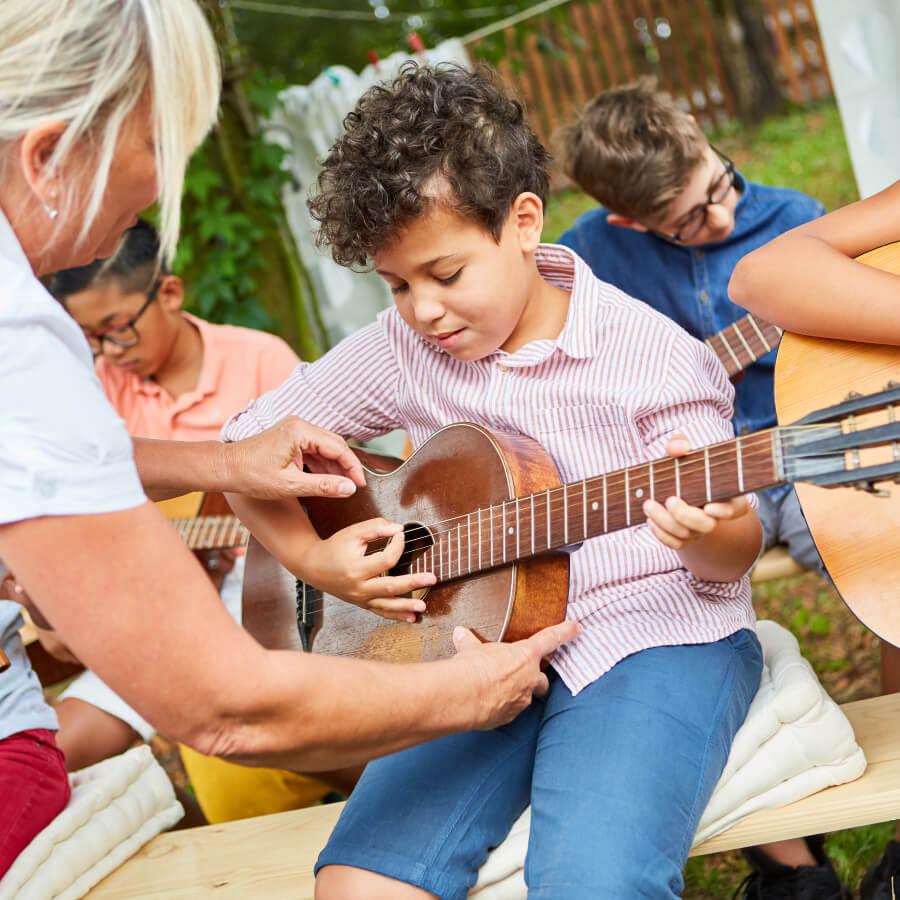 Teacher helps child learn to play the guitar